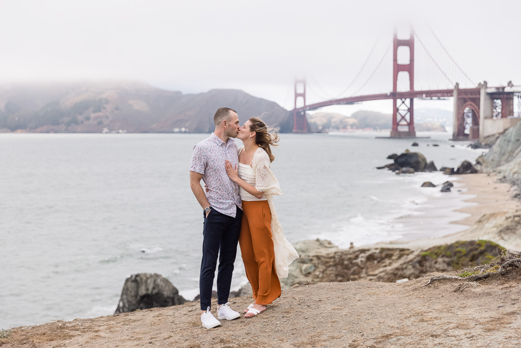 burnt orange dress engagement photo in front of foggy Golden Gate Bridge backdrop
