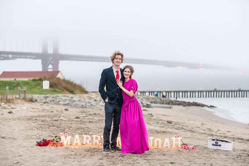 proposal photo on the Crissy Field beach in front of a foggy Golden Gate Bridge