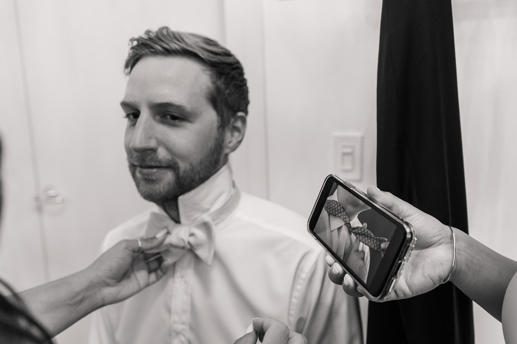 groomsman watching video of how to put bow tie on