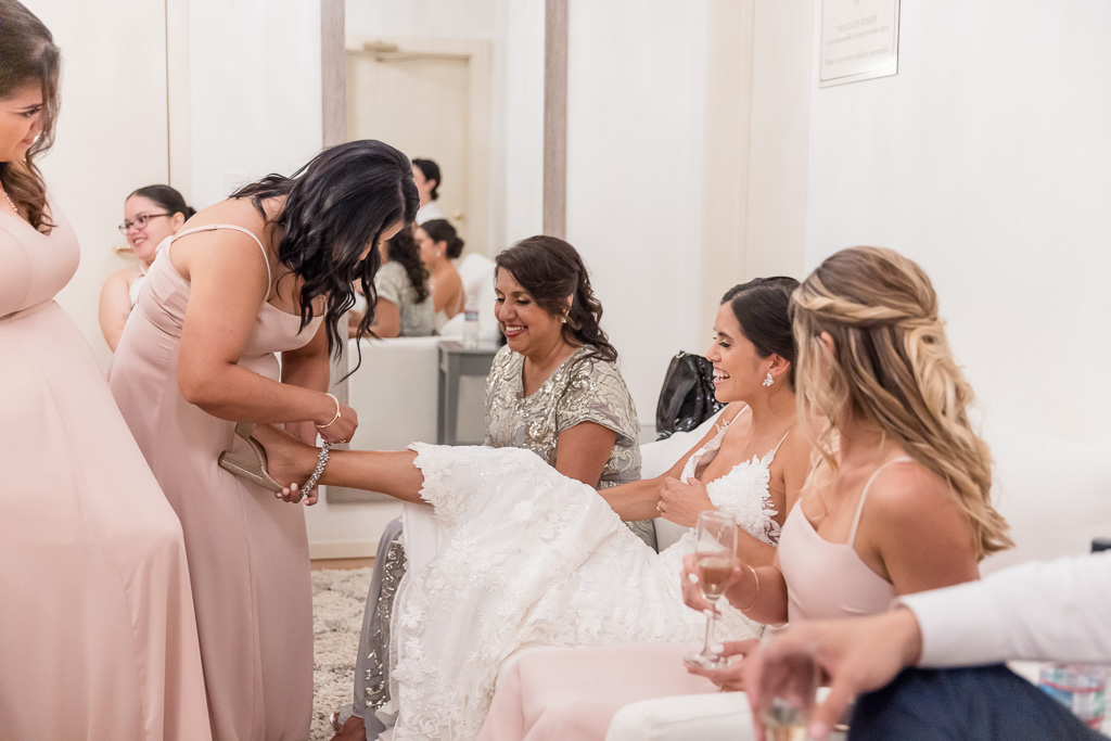 bridesmaid helping bride put her shoe on