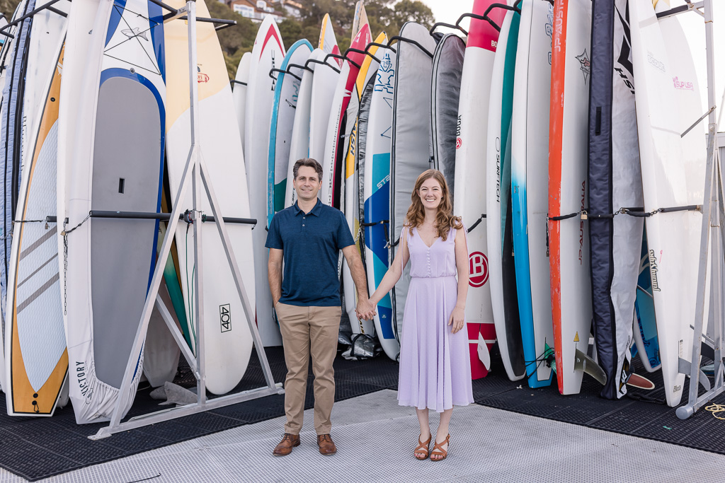 couple portrait in front of colorful surfboards
