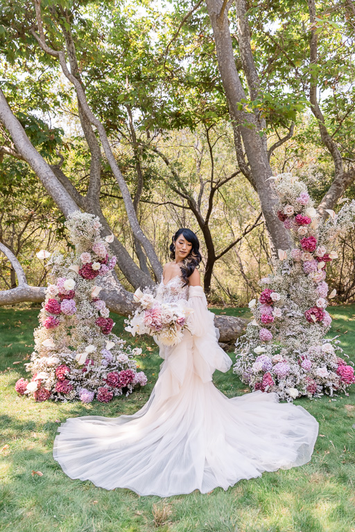 dreamy wedding bride in front of a lush floral arch