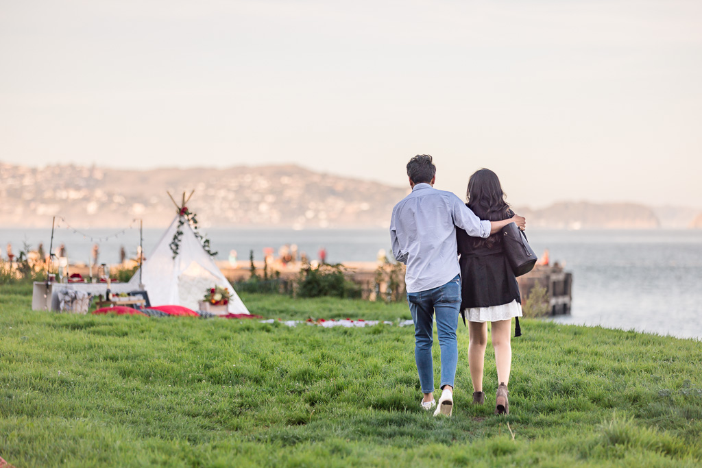 couple walking towards picnic with teepee set up by Joy’s Delightful Creations