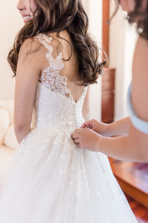 bridesmaid helping to button up bride’s dress