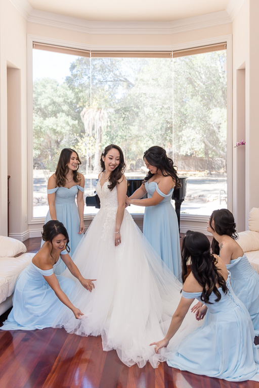 bridesmaids helping bride put on her dress