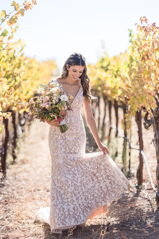 bride playing with her dress in vineyards