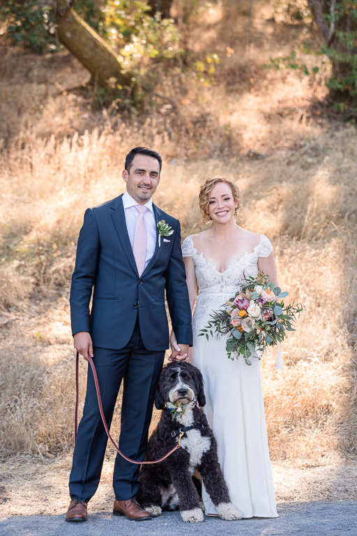bride, groom, and dog family photo on wedding day