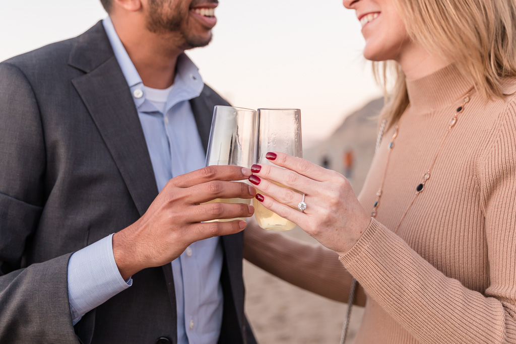 clinking champagne glasses and showing off engagement ring
