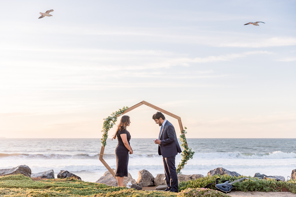 Pacifica coastline sunset surprise proposal in front of heptagonal arbor with flowers