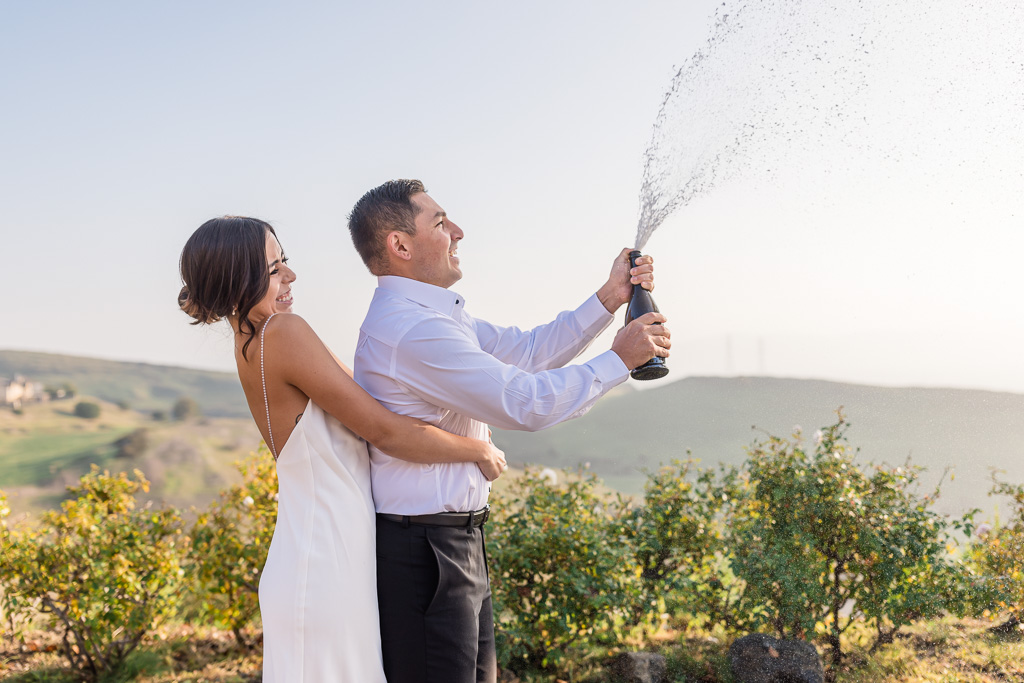spraying champagne in engagement photos