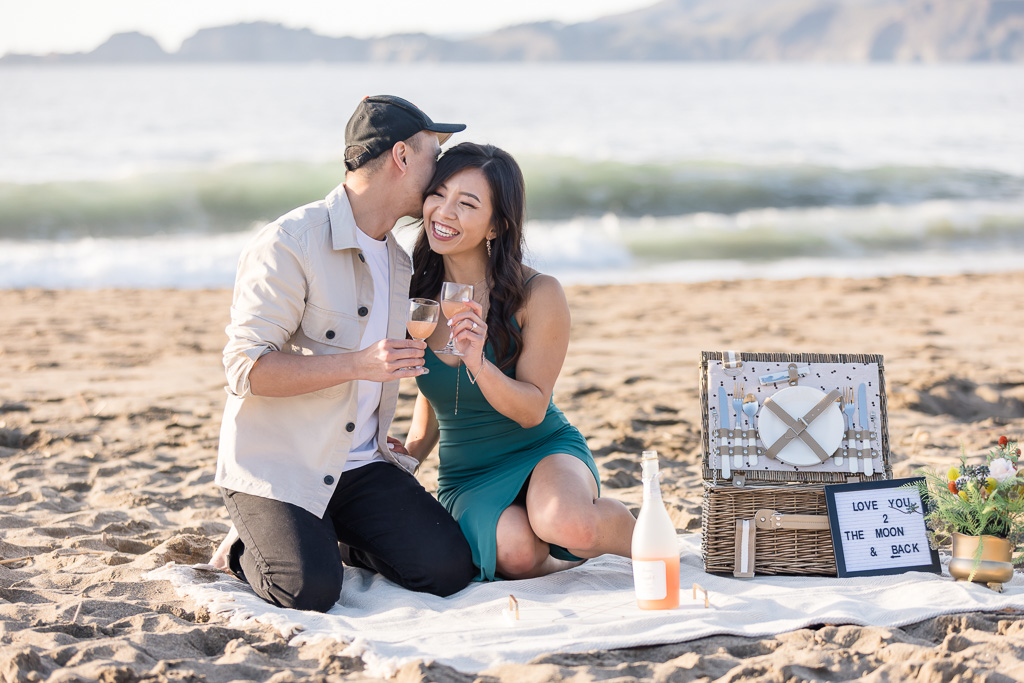 cute picnic engagement photo on the beach