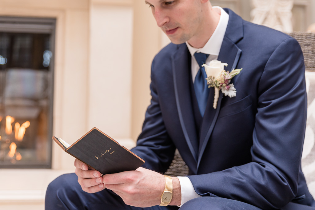 groom reviewing his vows from a custom wooden vow book