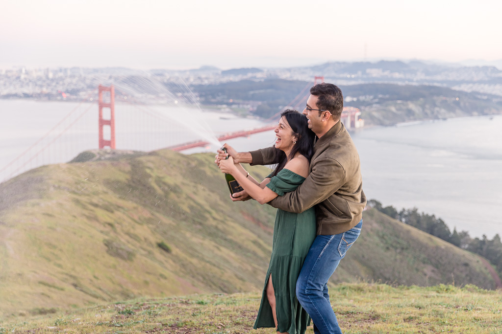 couple popping champagne with the Golden Gate Bridge behind them