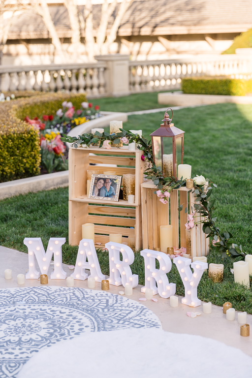 proposal decor with wooden frame, photos, and light-up marry me sign letters