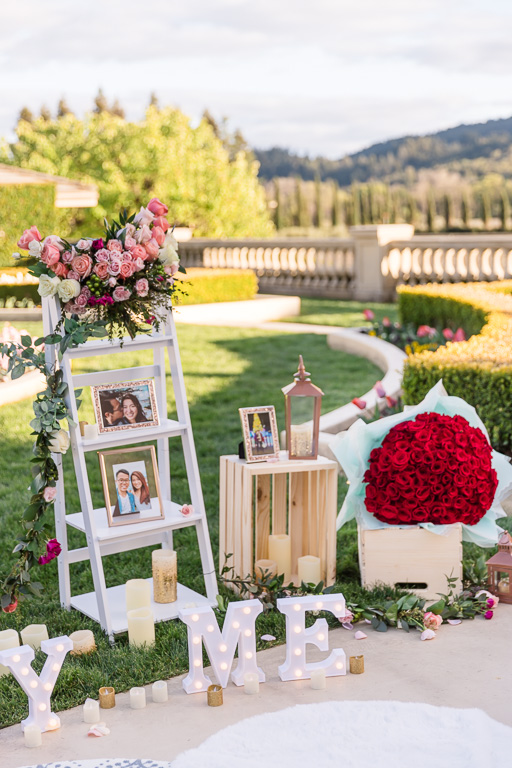 proposal setup with photos, flower bouquets, and a marry me sign