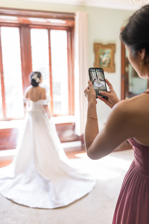 bridesmaid taking a cellphone photo of the bride
