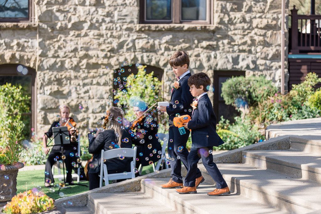 ring bearer walking down the aisle blowing bubbles