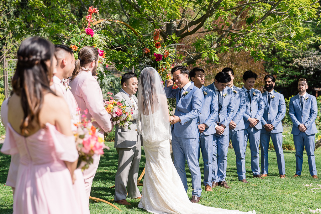 groom wiping a tear during outdoor ceremony
