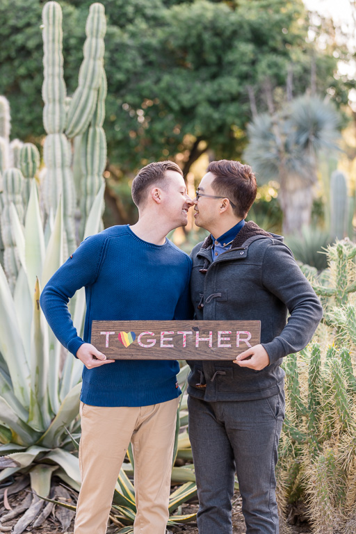 gay couple holding wooden together sign