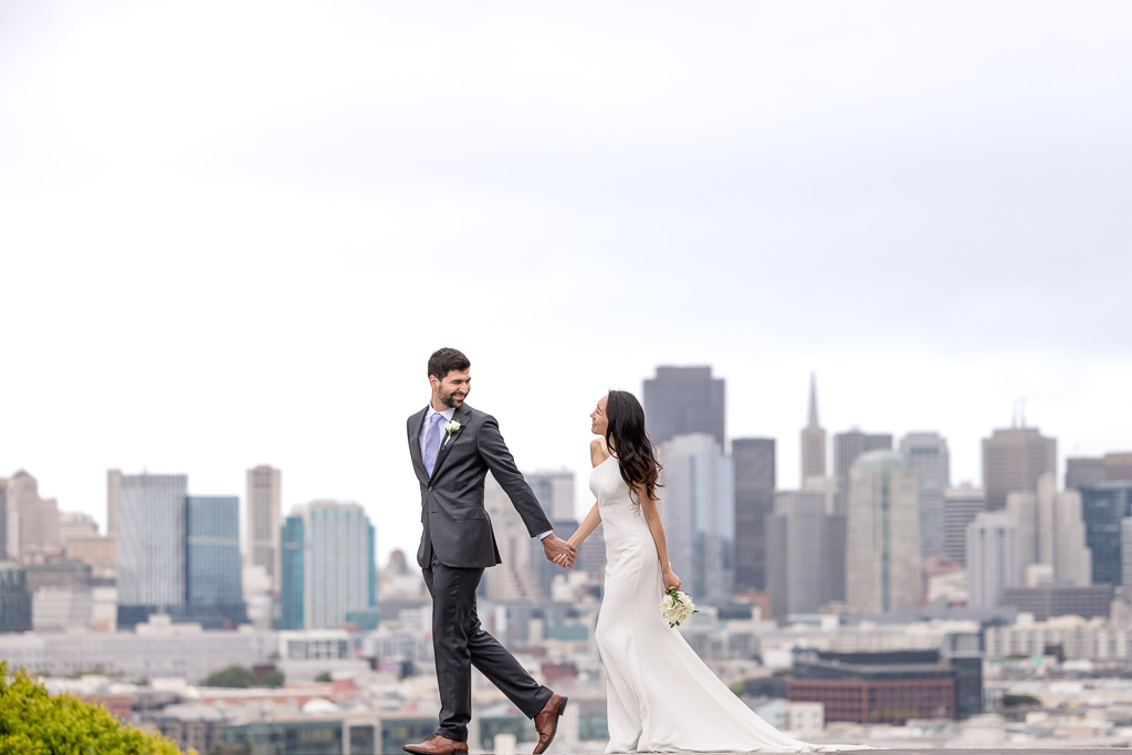 newlywed portrait in suit and wedding gown in front of SF skyline
