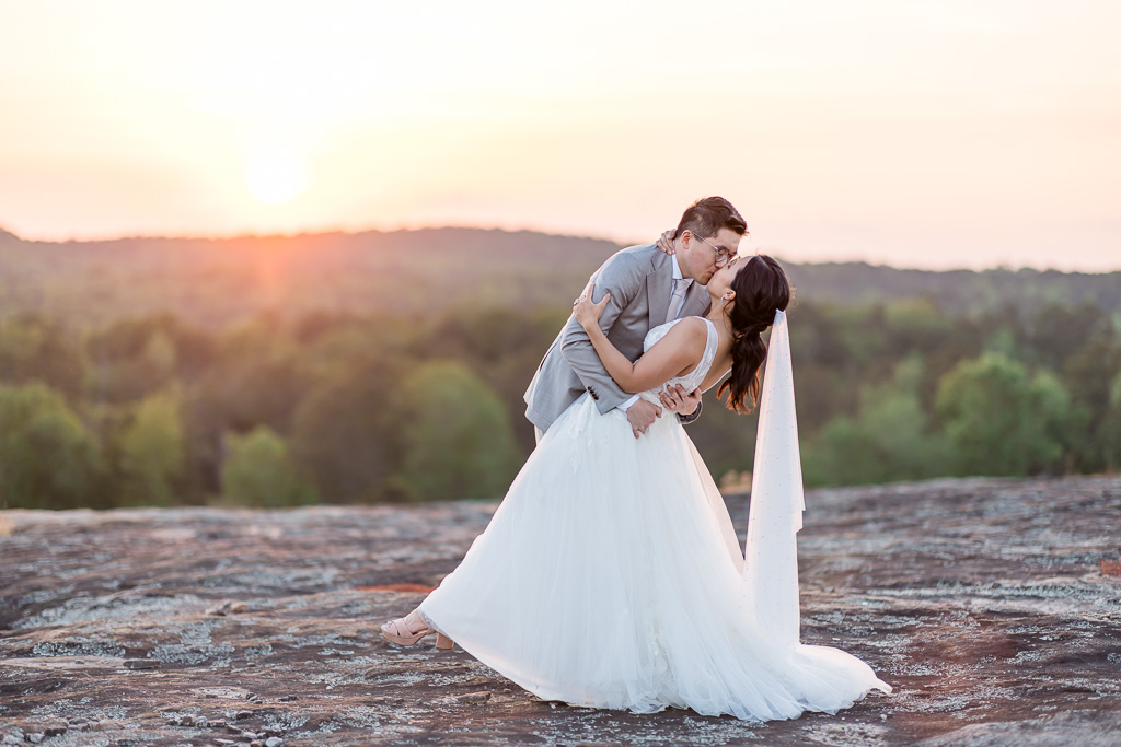 sunset dip and kiss wedding photo atop a mountain