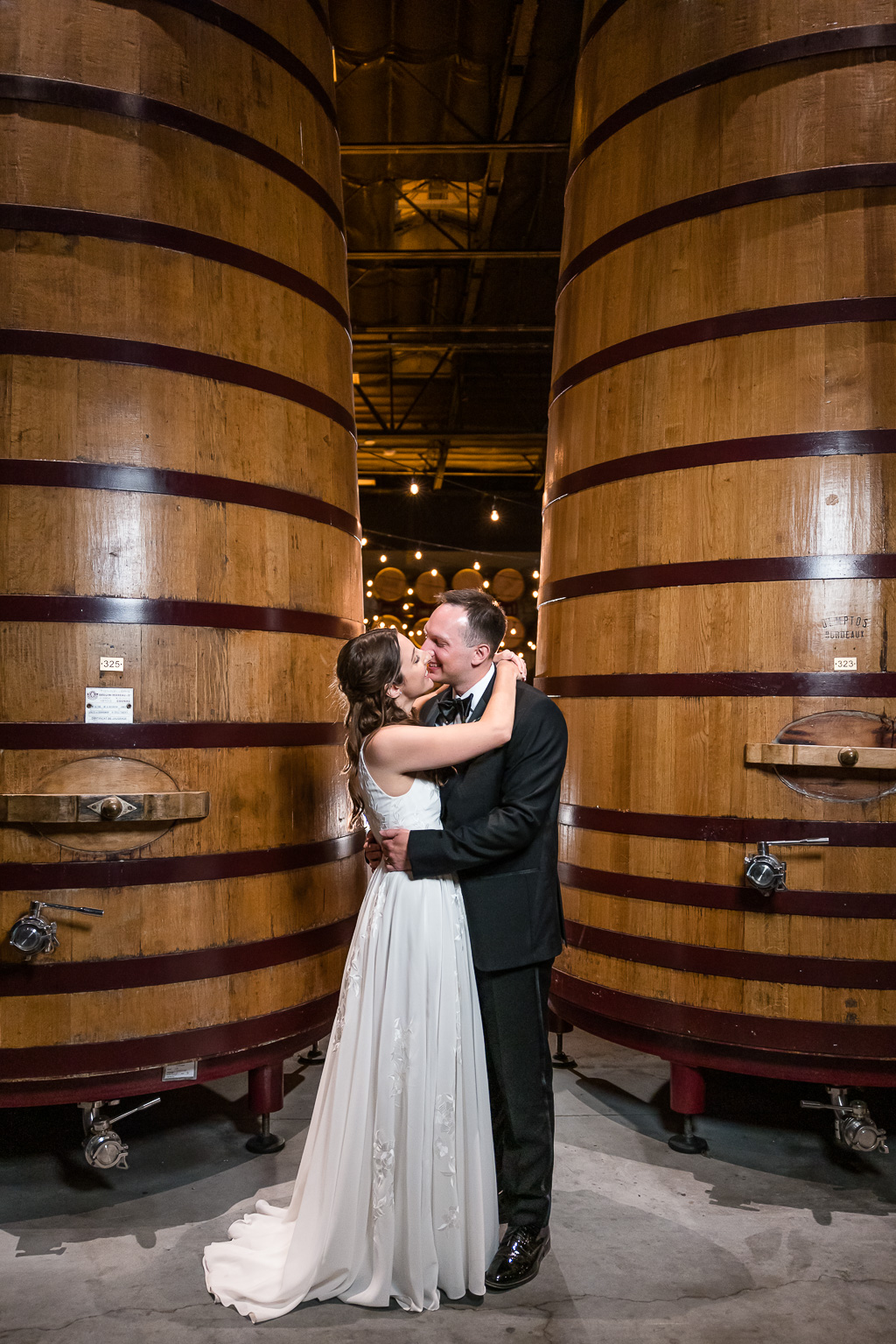 creative nighttime wedding photo in front of huge wine barrels
