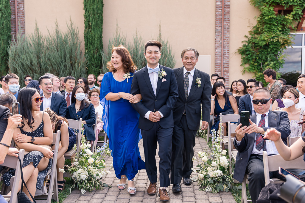 groom walking down the aisle with both of his parents