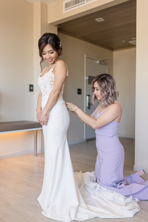 bridesmaid helping bride with her dress
