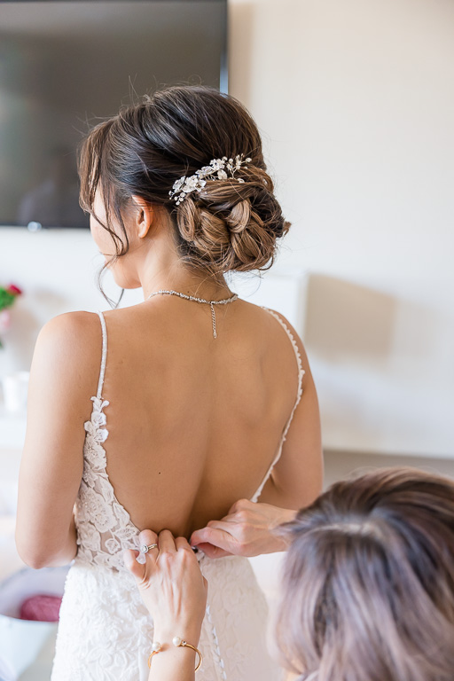 bridesmaid helping bride with the back of her dress
