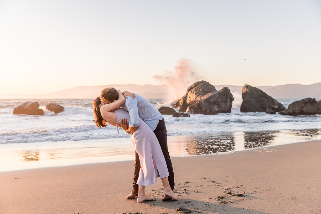 dipping engagement photo with ocean splashes in the background