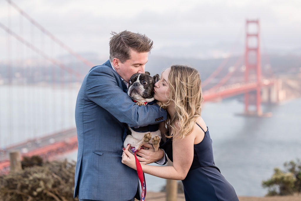 couple kissing their French Bulldog in front of the Golden Gate Bridge