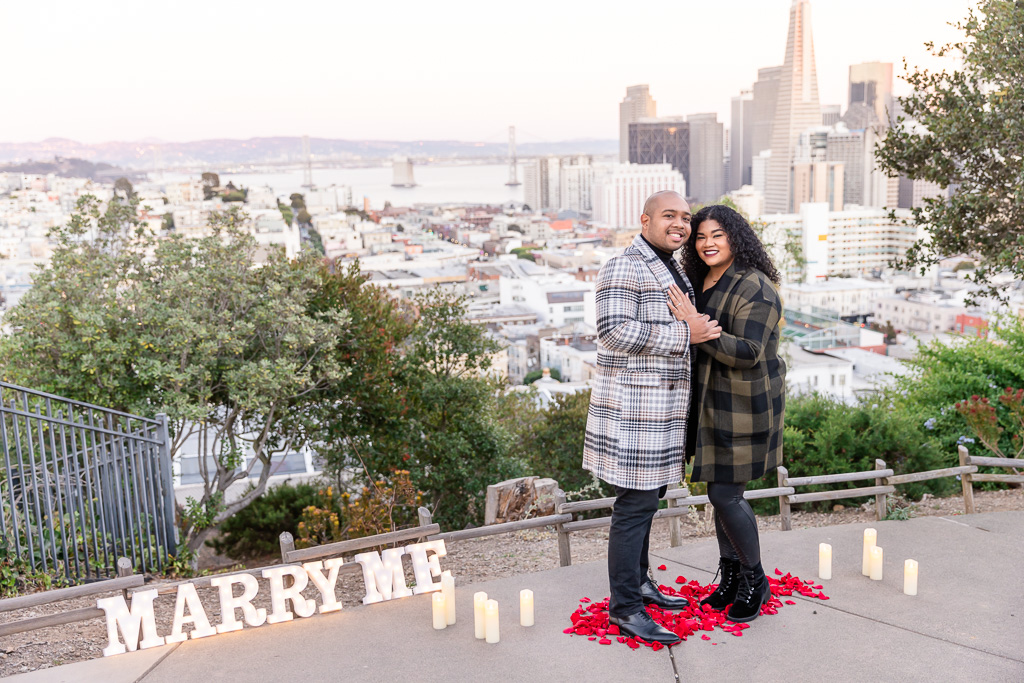 newly-engaged couple in front of the San Francisco skyline at sunset