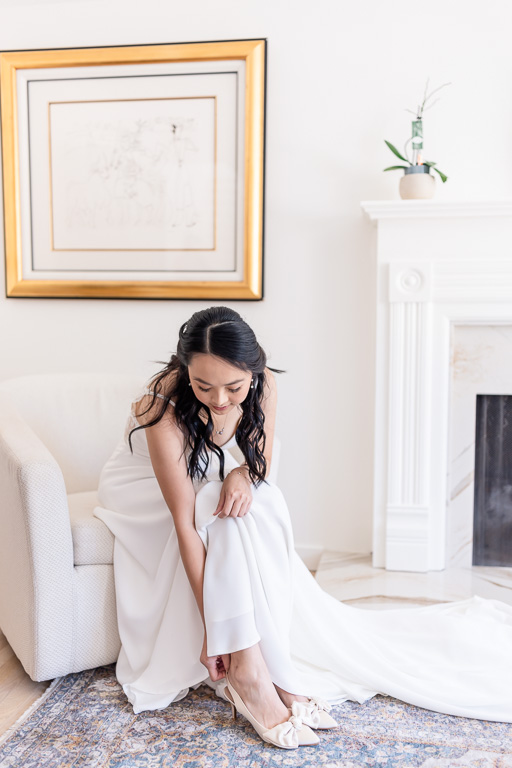 clean white photo of bride putting her shoes on