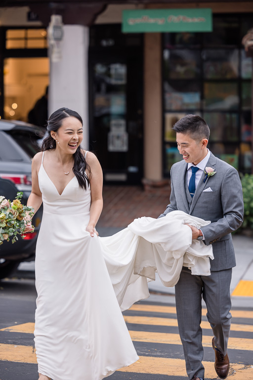 candid photo of newlywed bride and groom crossing the street at a crosswalk