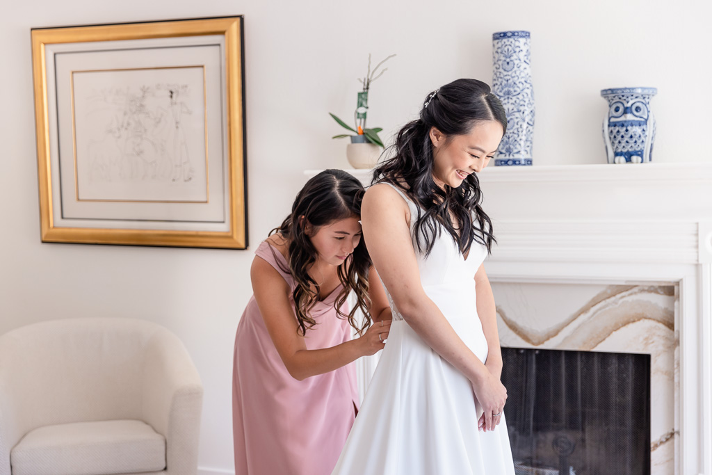 bridesmaid helping button up bride’s dress