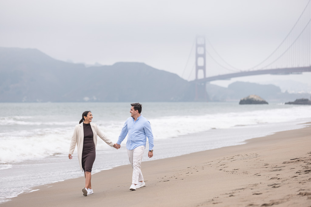 couple walking on the beach in front of the Golden Gate Bridge