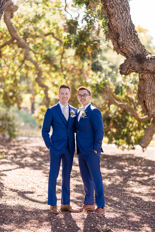 two grooms looking handsome under an oak tree