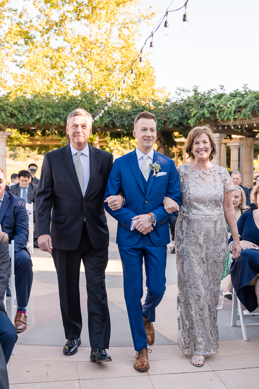 groom walking down the aisle with his mom and dad