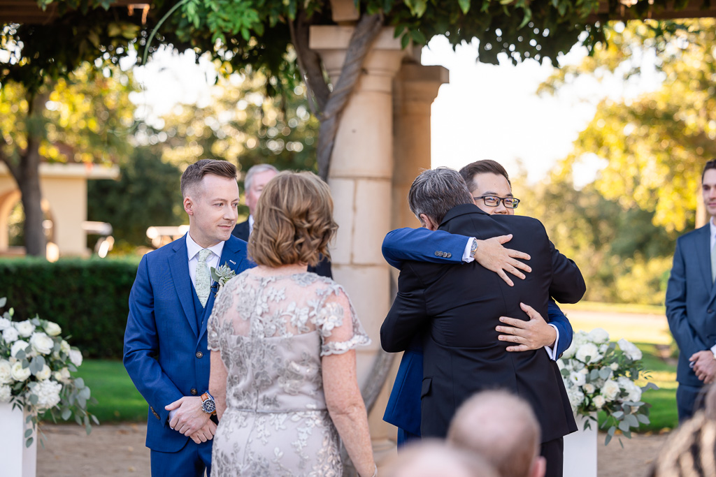 groom hugging the father of the other groom