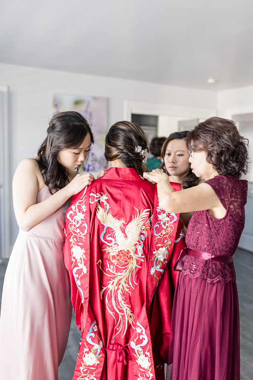 ladies helping the bride into her red dress