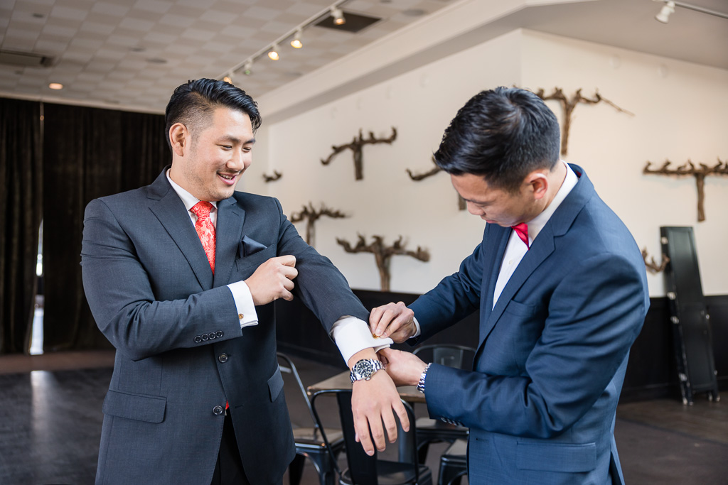 best man helping groom with cuff links