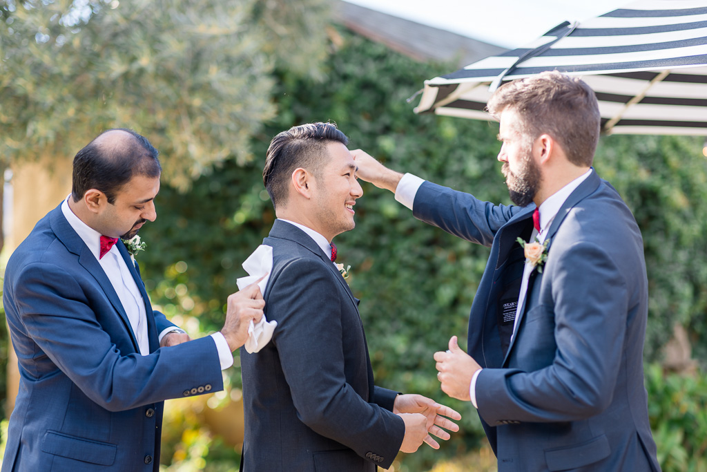 groomsmen helping wipe off the groom