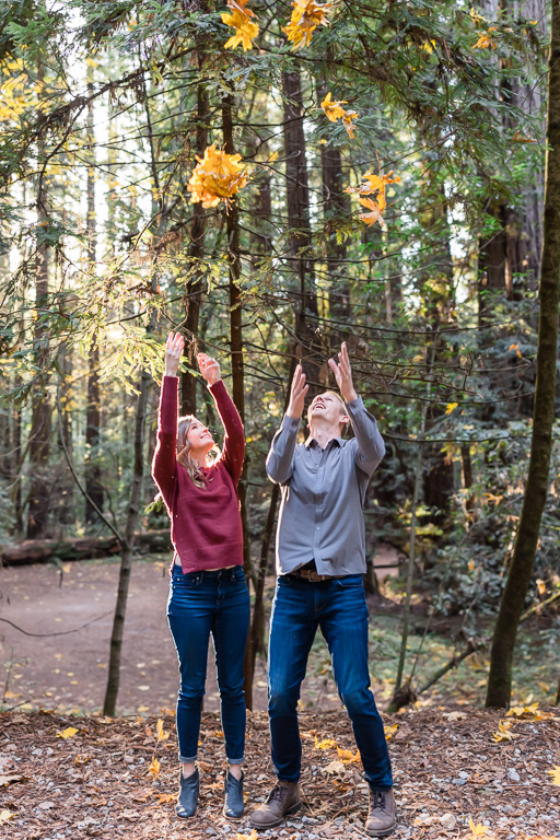 fun fall-themed engagement photos tossing up orange and yellow leaves into the air