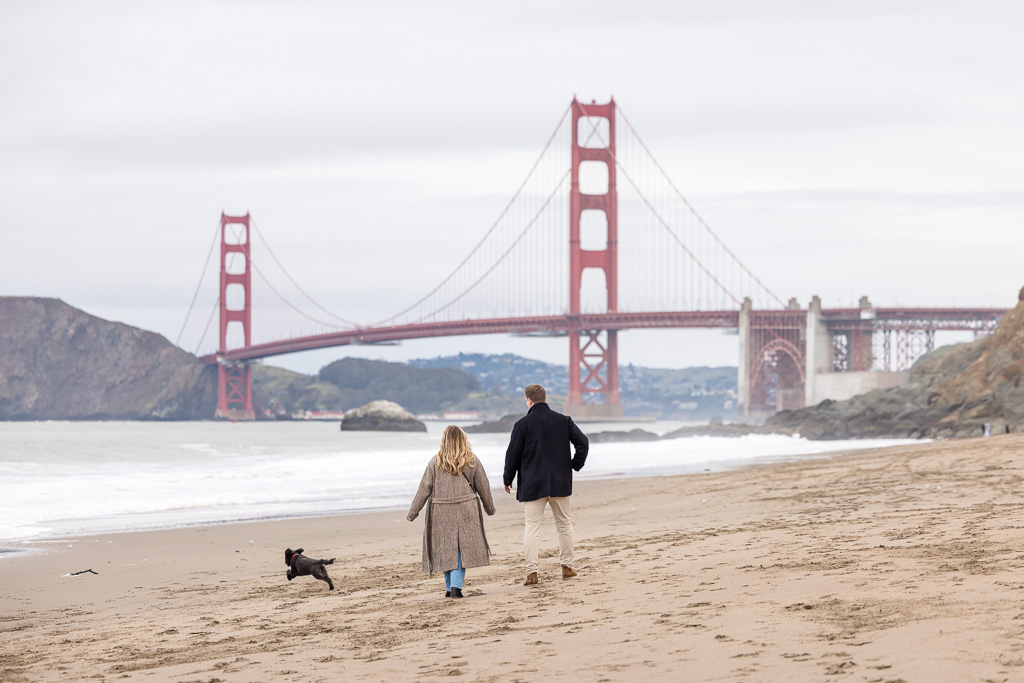 Couple walking along Baker Beach with cute dog next to them