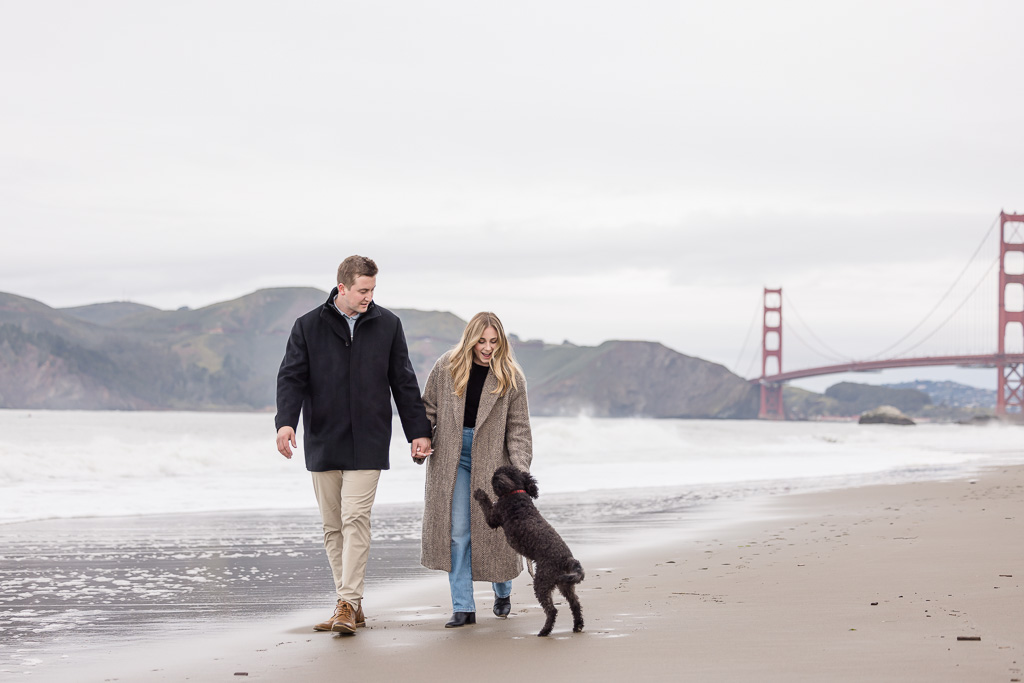 engagement photos with dog on beach in front of Golden Gate Bridge