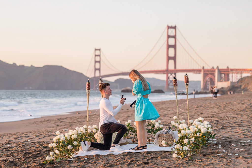 Romantic Baker Beach sunset surprise proposal with long-stemmed white roses