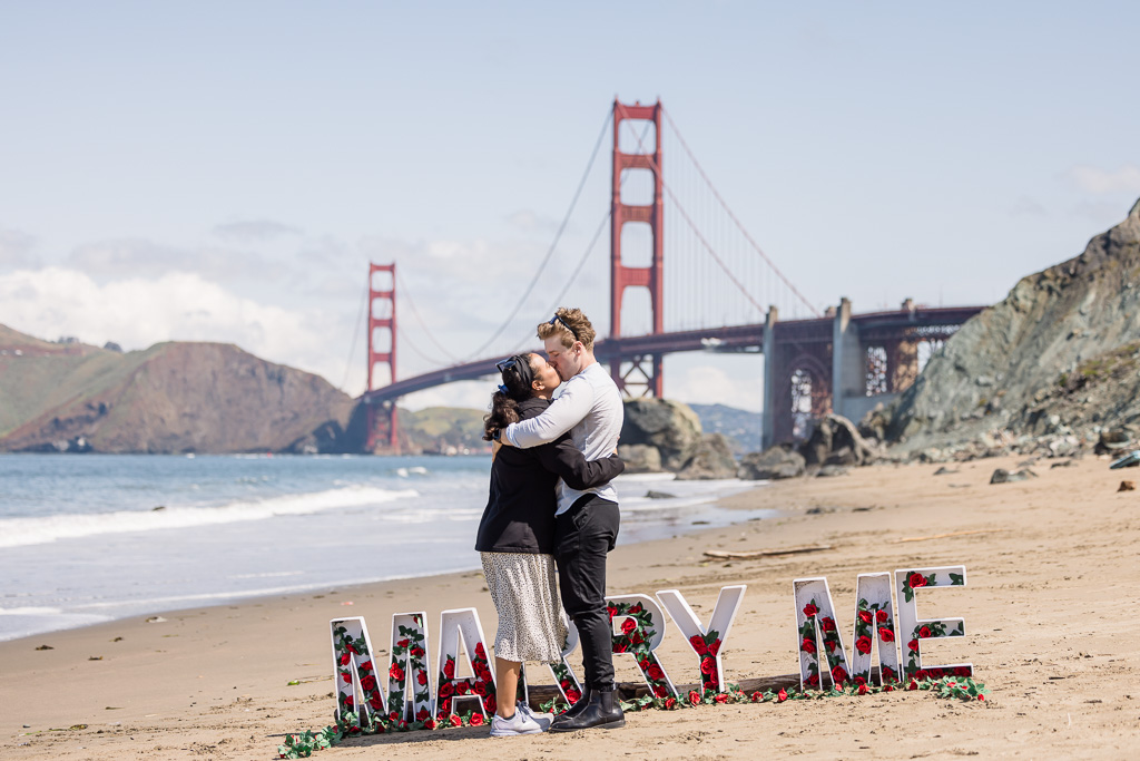 Golden Gate Bridge surprise proposal with standing marry me letters and flowers