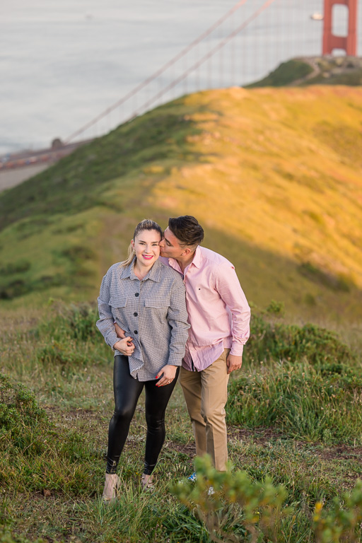 couple posing for photos on a hill near the Golden Gate Bridge