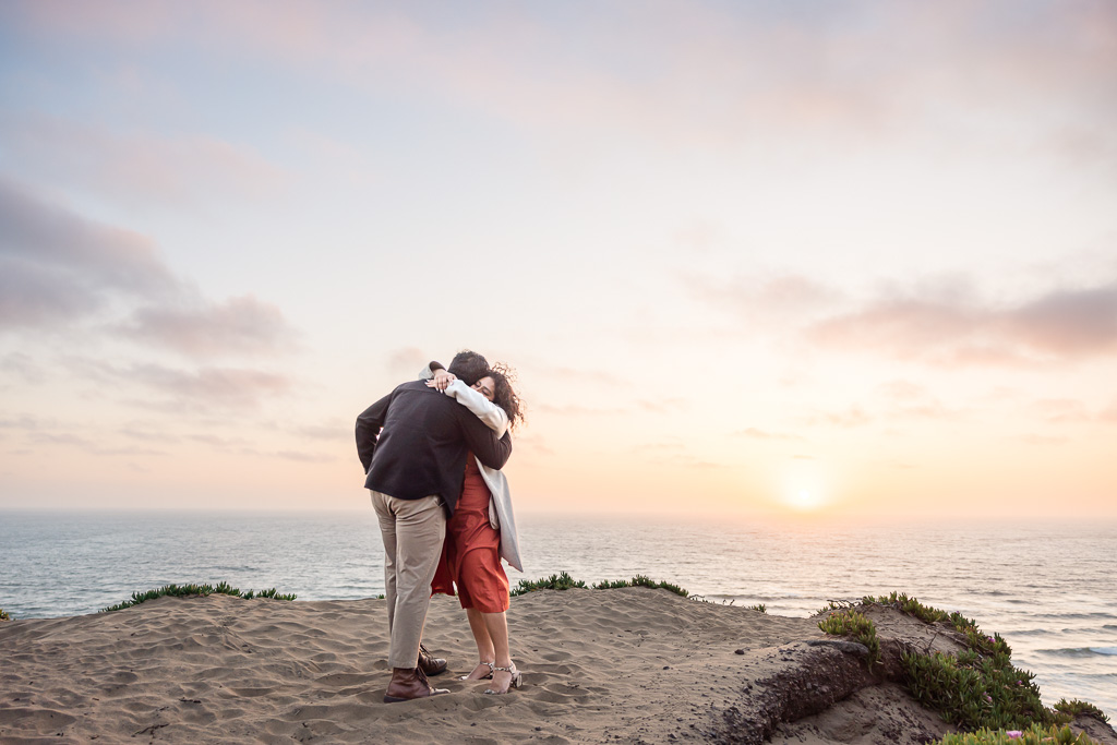 couple hugging on cliffside at sunset