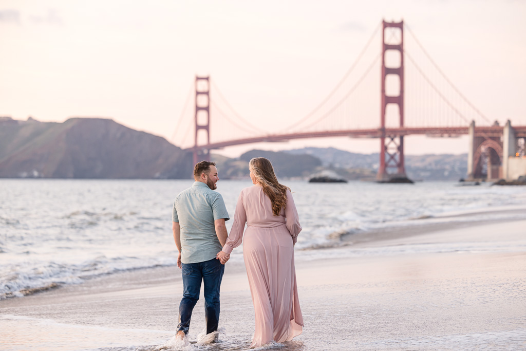 couple walking towards Golden Gate Bridge in the ocean water